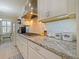 Kitchen with white cabinets, granite countertops, stainless range hood, and tile backsplash at 3687 Farm Bell Pl, Lake Mary, FL 32746