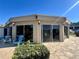 View of the community clubhouse with outdoor seating, surrounded by green vegetation and a paver patio at 400 E Orlando Ave # 10, Ocoee, FL 34761