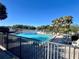 Community pool overlooking the lake with poolside seating and beautiful palm trees against a clear blue sky at 400 E Orlando Ave # 10 C, Ocoee, FL 34761