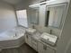 Bathroom features double sinks, white cabinets, granite countertops, and large tub at 403 Britten Dr, Kissimmee, FL 34758