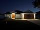 Night view of house with a well-manicured lawn, beautiful front doors, and a two car garage at 403 Britten Dr, Kissimmee, FL 34758