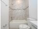 Modern bathroom showcasing marble-tiled walls, a combination tub/shower, a white vanity, and contemporary fixtures at 4765 Sw 128Th St, Ocala, FL 34473