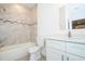 Modern bathroom showcasing marble-tiled walls, a combination tub/shower, a white vanity, and contemporary fixtures at 4765 Sw 128Th St, Ocala, FL 34473