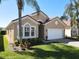 Charming home boasts a tile roof, two-car garage, lush lawn, and mature palm trees enhancing its curb appeal at 631 Tuscan Hills Blvd, Davenport, FL 33897