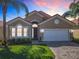 Beautiful single-story home featuring a tile roof, a two-car garage, and a well-manicured lawn with palm trees at 631 Tuscan Hills Blvd, Davenport, FL 33897