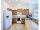 Well-lit kitchen with wood cabinets, white appliances, and durable tile flooring, ideal for culinary enthusiasts at 631 Tuscan Hills Blvd, Davenport, FL 33897