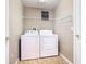 Practical laundry room with washer, dryer, overhead shelving, and tiled floors, creating an organized space at 631 Tuscan Hills Blvd, Davenport, FL 33897