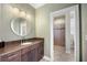 Bathroom with wooden cabinet, stone countertop, round mirror, and a glass door shower room at 743 Mills Estate Pl, Chuluota, FL 32766