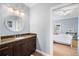 Bathroom with wooden cabinet, stone countertop, round mirror, and an open doorway to a bedroom at 743 Mills Estate Pl, Chuluota, FL 32766
