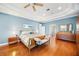 This main bedroom features blue walls, a ceiling fan, and a wood bed, complete with a bench, for an elegant space at 743 Mills Estate Pl, Chuluota, FL 32766