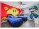 Bright bedroom with two beds, ceiling fan, and a vibrant Super Mario Brothers themed wall mural at 8959 Stinger Dr, Champions Gate, FL 33896