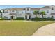 Well-manicured townhouse with lush green lawn, featuring a covered entryway and mature palm trees at 8959 Stinger Dr, Champions Gate, FL 33896