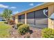 Rear exterior of a home showing a screened-in lanai, well-maintained landscaping, and a clear blue sky at 9491 Sw 98Th Ct, Ocala, FL 34481