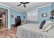 Cozy bedroom featuring wood floors, blue walls, a ceiling fan, and an inviting armchair at 9491 Sw 98Th Ct, Ocala, FL 34481