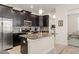 Elegant kitchen equipped with stainless steel appliances, dark cabinetry, granite countertops, and an island with bar seating at 9844 Pecan Hickory Way, Orlando, FL 32832