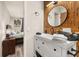 Stylish bathroom featuring a bamboo accent wall, modern vanity with black hardware, and round mirror at 1061 Radford Dr, Deltona, FL 32738