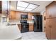 Kitchen with wooden cabinets, black appliances, and a spacious tile floor under a skylight at 1511 Grandview Blvd, Kissimmee, FL 34744