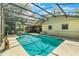 A view of the pool showcasing the screened enclosure, the house, and the mature trees in the backyard at 1511 Grandview Blvd, Kissimmee, FL 34744