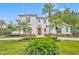 Beautiful two-story home featuring a red tile roof, white stucco and meticulously landscaped front yard with tropical palm trees at 1630 Lasbury Ave, Winter Park, FL 32789