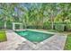 Beautiful backyard pool with travertine tile and white pergola surrounded by lush greenery at 1630 Lasbury Ave, Winter Park, FL 32789