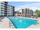 Community pool surrounded by lounge chairs and multiple story apartment buildings at 16300 County Road 455 # 704, Montverde, FL 34756