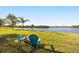 Serene backyard featuring two blue chairs on a sunny lawn, looking out to a calm lake view at 1810 Trophy Bass Way, Kissimmee, FL 34746