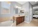 This bathroom features a brown vanity cabinet with a large mirror, vanity lights, a corner tub and a window at 1810 Trophy Bass Way, Kissimmee, FL 34746