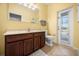 This yellow-toned bathroom features a toilet and sink with a brown vanity, and has a door to the outside at 1810 Trophy Bass Way, Kissimmee, FL 34746