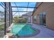 Beautiful screened pool area with lush foliage, a clear blue sky, and neutral colors at 2215 Mallard Creek Cir, Kissimmee, FL 34743