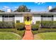 Close-up of bright yellow front door with glass accents, brick walkway, and manicured landscaping at 2424 Shrewsbury Rd, Orlando, FL 32803