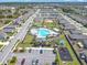 Community pool featuring a playground, lounge chairs, palm trees and a parking lot is captured aerially at 297 Citrus Isle Loop, Davenport, FL 33837