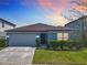 Well-maintained single-story home with a two-car garage and lush green front yard under a colorful sunset at 297 Citrus Isle Loop, Davenport, FL 33837