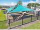 An aerial view shows a shaded picnic table within a fenced in playground at 297 Citrus Isle Loop, Davenport, FL 33837