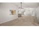 Open-concept living room showcasing a kitchen view, modern lighting, and neutral carpet throughout the space at 3093 S Horizon Pl, Oviedo, FL 32765