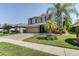 Charming two-story home with a brick driveway, palm trees, manicured lawn, and neutral paint with purple shutters at 321 Cape Sable Dr, Orlando, FL 32825