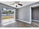 This bedroom has wood-look flooring, a modern ceiling fan, and a sliding glass door with a view of the yard at 4458 Goldenrain Ct, Orlando, FL 32808