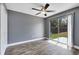 Bright bedroom featuring hardwood flooring, gray walls, modern ceiling fan, and sliding glass door to the backyard at 4458 Goldenrain Ct, Orlando, FL 32808