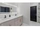 Elegant bathroom featuring double sinks, a large LED mirror, quartz counters, and a black accent door at 645 Riverwoods Cir, Orlando, FL 32825