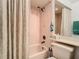 A pink-tiled bathroom with a shower-tub combo and a patterned shower curtain, a sink, and a toilet at 11624 Peach Grove Ln, Orlando, FL 32821