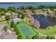 Aerial view of a community tennis court and pool, surrounded by lush greenery and a tranquil lake at 124 Windsor Cresent St, Winter Springs, FL 32708