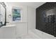 Modern bathroom with a white vanity, black fixtures, subway tile, and a black tiled accent wall above the bathtub at 1518 Coletta Dr, Orlando, FL 32807