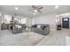 Bright living room with grey sofas, ceiling fan, and light grey wood flooring at 1610 Stephanie Ln, Lakeland, FL 33813