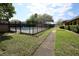 Community pool with a black metal fence, surrounded by green grass and lush trees at 209 Esplanade Way # 109, Casselberry, FL 32707