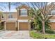 Charming two-story townhome featuring a tan stucco exterior, attached garage, and mature landscaping for added curb appeal at 2864 Polana St # 104, Orlando, FL 32835