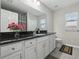 Bright bathroom featuring a large vanity with black countertop, white cabinets, and a wide mirror, creating a fresh aesthetic at 3176 Sw 127Th St, Ocala, FL 34473