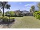 Lush backyard with manicured lawn and garden leading to the home with glass-enclosed patio at 3402 Cocard Ct, Windermere, FL 34786