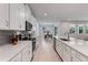 A modern kitchen overlooks a dining area and features stainless steel appliances, quartz countertops, and white cabinetry at 3418 Douglas Fir Dr, Apopka, FL 32703