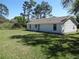 Back exterior of home with a green lawn, and shade trees on a sunny day at 445 Live Oak Ave, Chuluota, FL 32766