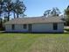 Rear view of the house featuring white siding, a gray roof, and well-maintained lawn at 445 Live Oak Ave, Chuluota, FL 32766