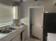 Kitchen with a double sink, white cabinets, black appliances, and a door leading to the bathroom at 4845 Elese St, Orlando, FL 32811